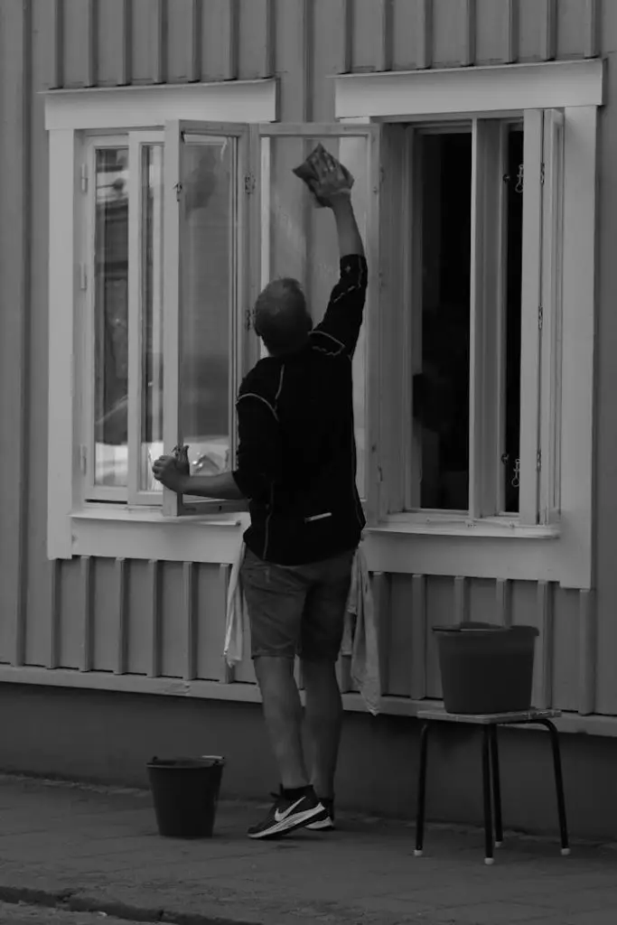 A man cleans windows on a street in Jonkoping, Sweden, in a monochrome setting.